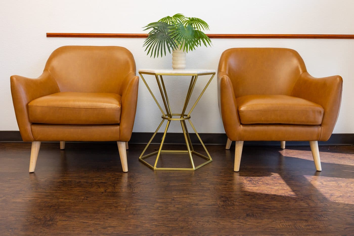 Two cognac leather chairs and a gold side table in the Soleil Dental Mesquite waiting room