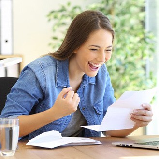 Young woman celebrating after looking at her dental bill