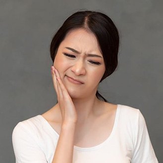 woman holding her cheek in pain